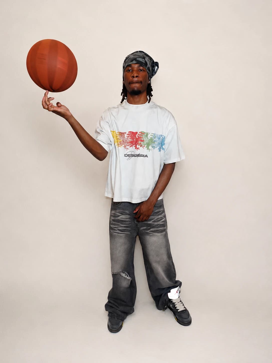 Standing full-length in the multicolor eagle tee, basketball balanced on a raised finger